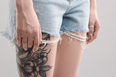 Woman with cool tattoos on grey background, closeup