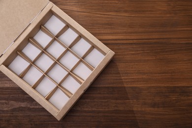 Photo of Empty packaging box with dividers on wooden table, top view. Space for text