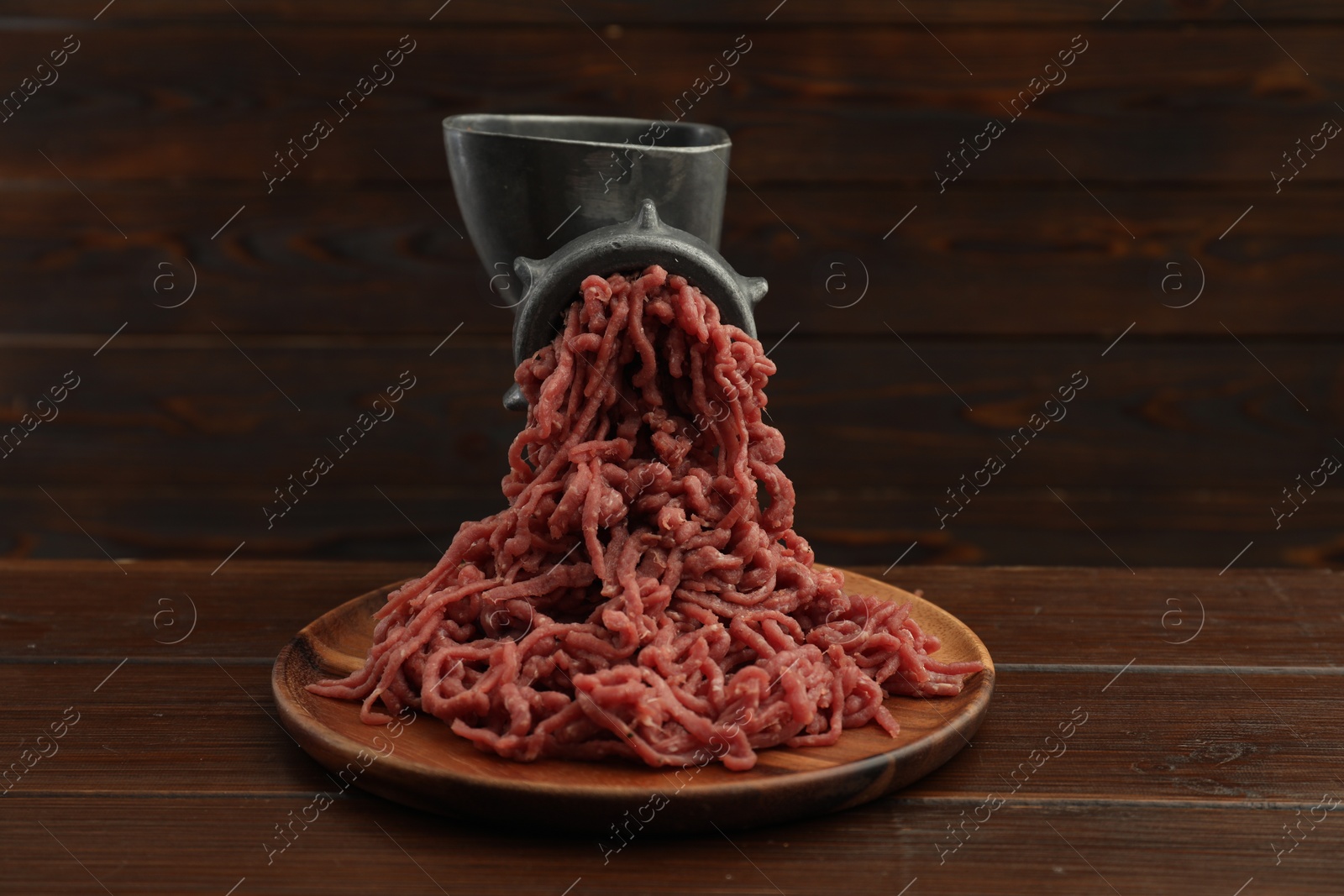 Photo of Meat grinder with beef mince on wooden table