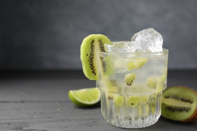 Photo of Glass of refreshing drink and cut kiwi on gray table, closeup. Space for text