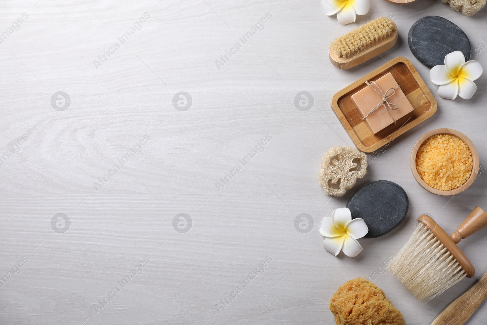 Photo of Flat lay composition with different spa products and flowers on light wooden table. Space for text