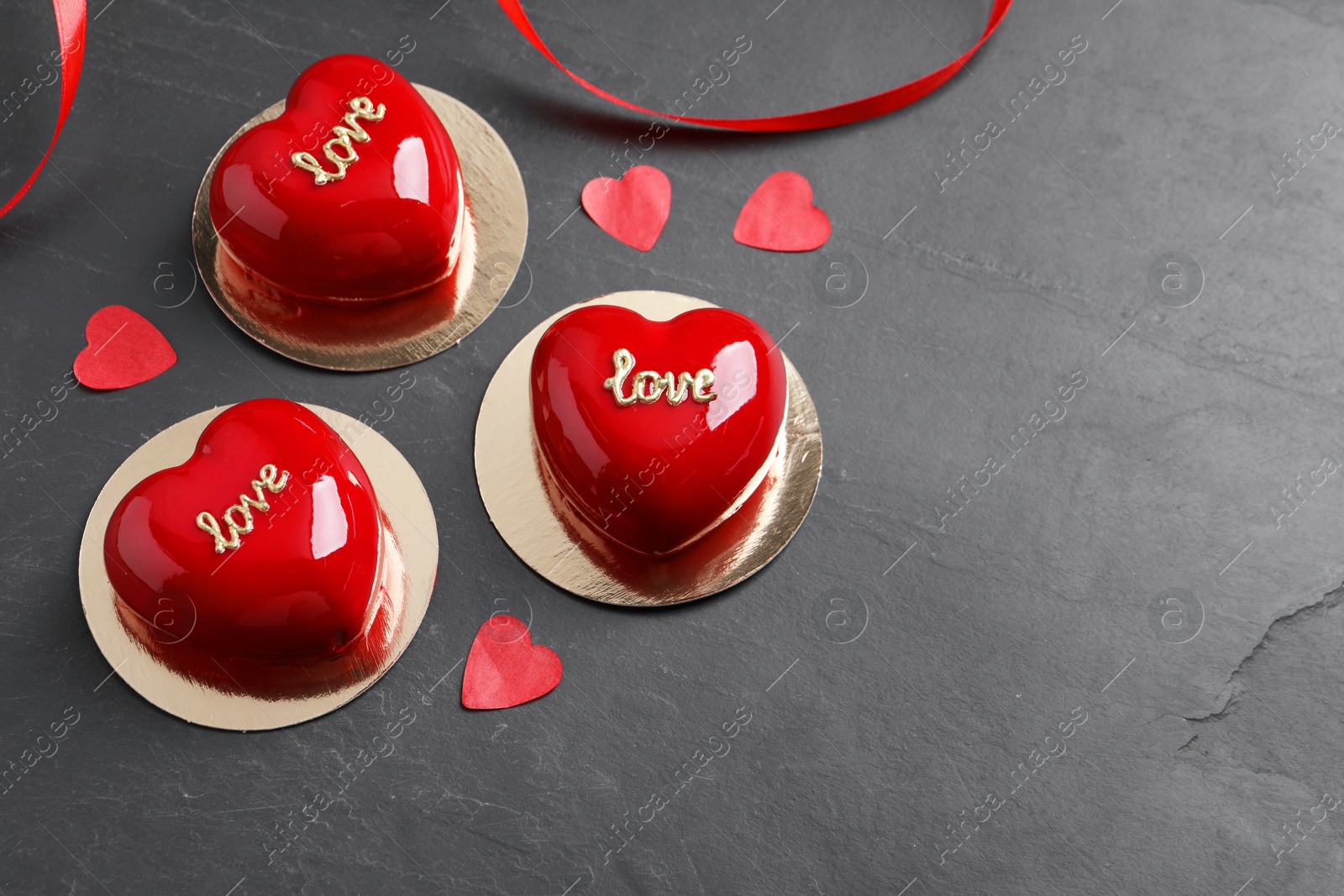 Photo of St. Valentine's Day. Delicious heart shaped cakes and confetti on black table. Space for text