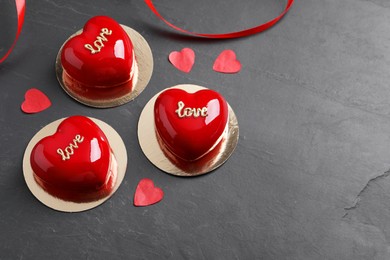 St. Valentine's Day. Delicious heart shaped cakes and confetti on black table. Space for text