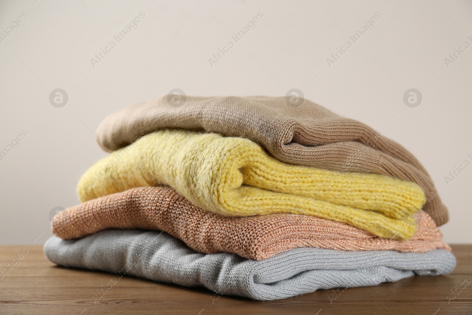 Photo of Stack of knitted sweaters on wooden table