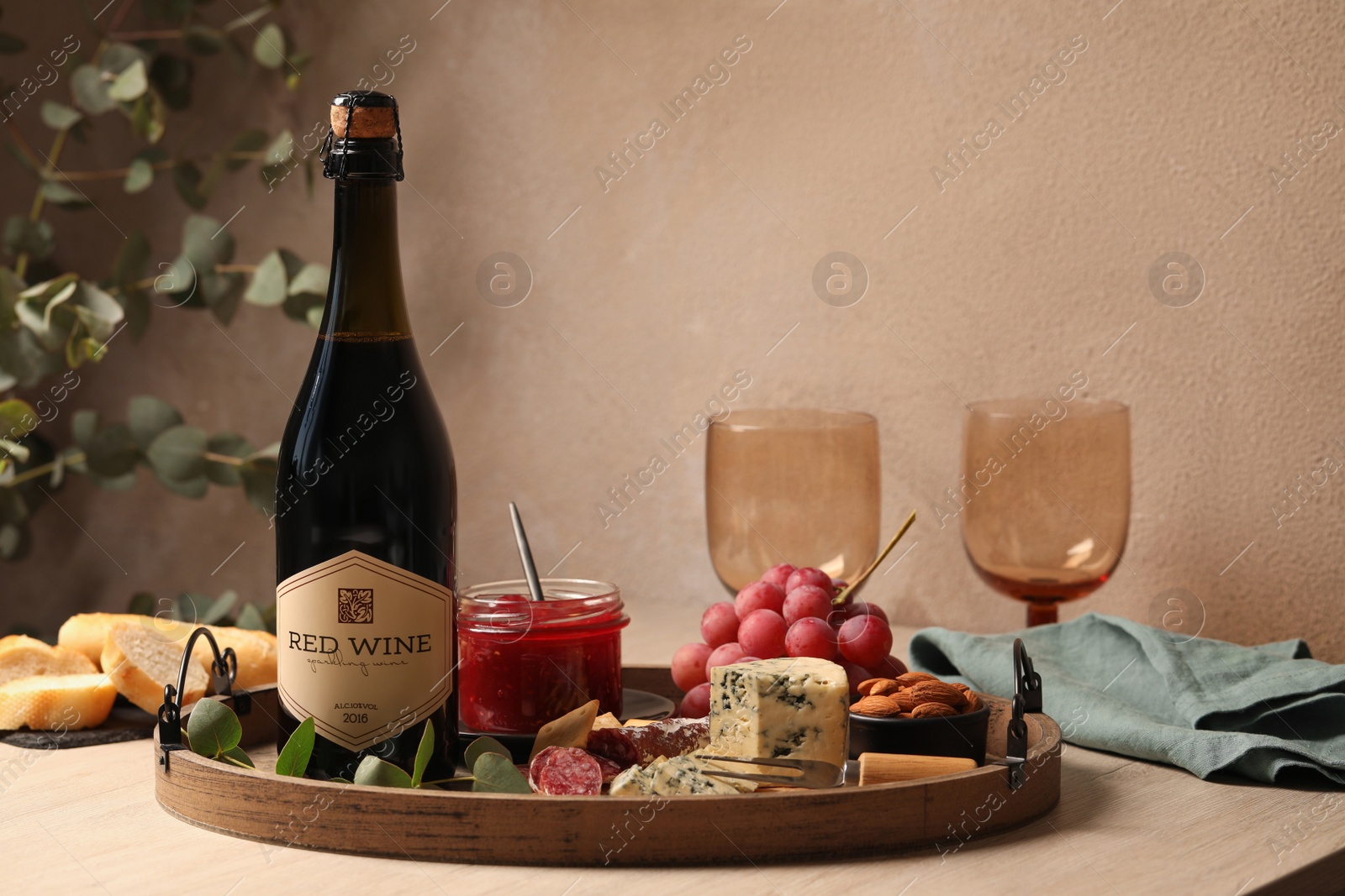 Photo of Bottle of red wine, glasses and delicious snacks on wooden table