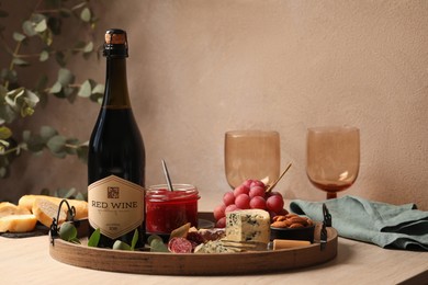 Photo of Bottle of red wine, glasses and delicious snacks on wooden table