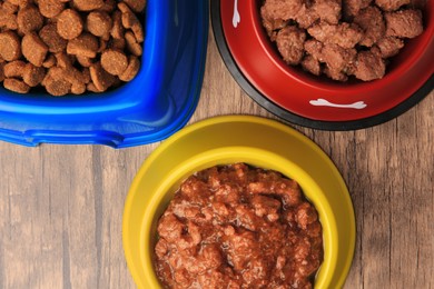 Photo of Dry and wet pet food in feeding bowls on wooden background, flat lay