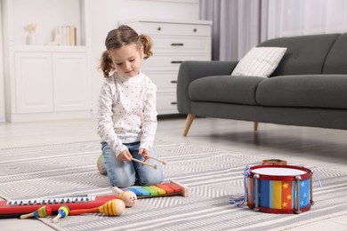 Photo of Little girl playing toy xylophone at home