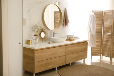 Photo of Modern bathroom interior with vessel sink and round mirror