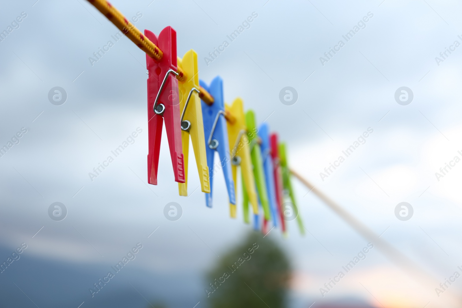 Photo of Colorful clothespins hanging on washing line outdoors