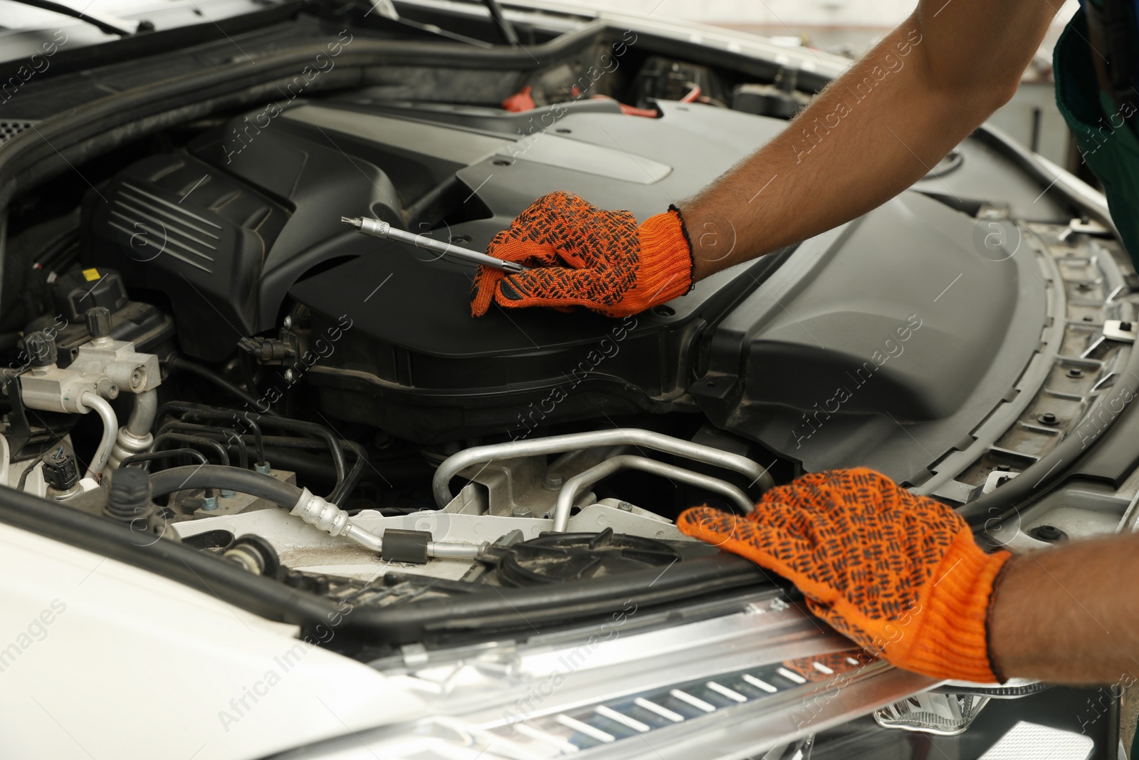 Photo of Professional mechanic fixing modern car at automobile repair shop, closeup