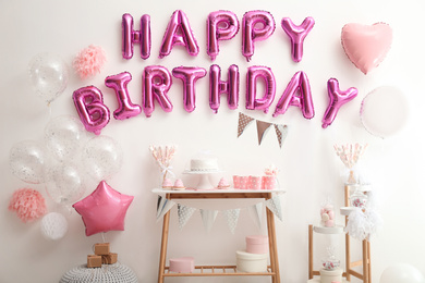Phrase HAPPY BIRTHDAY made of pink balloon letters on white wall