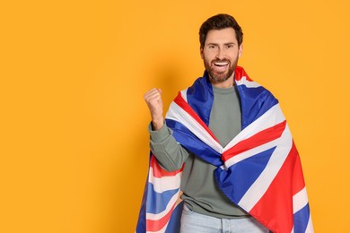 Emotional man with flag of United Kingdom on yellow background, space for text