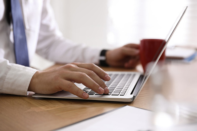 Man working with laptop in office, closeup of hand