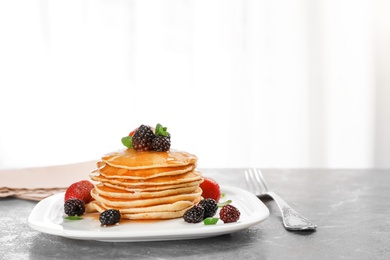 Photo of Delicious pancakes with berries and honey served for breakfast on table