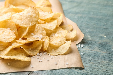 Photo of Delicious crispy potato chips on table, closeup with space for text