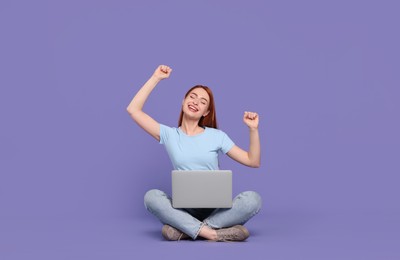 Happy young woman with laptop on lilac background