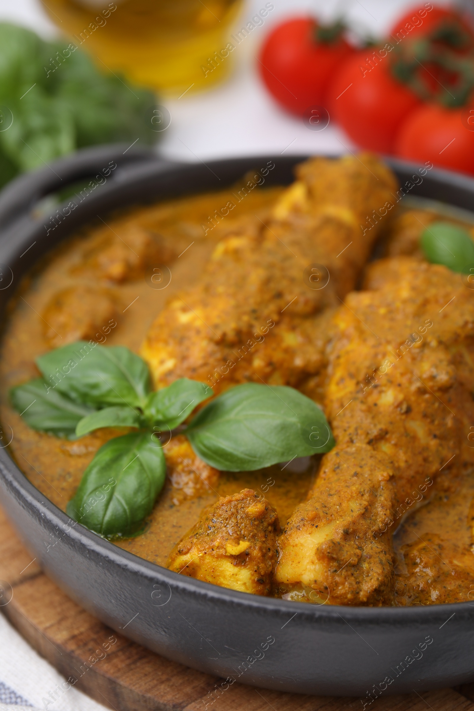 Photo of Delicious chicken with curry sauce and basil on table, closeup