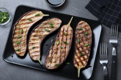 Photo of Delicious grilled eggplant halves served on grey table, flat lay
