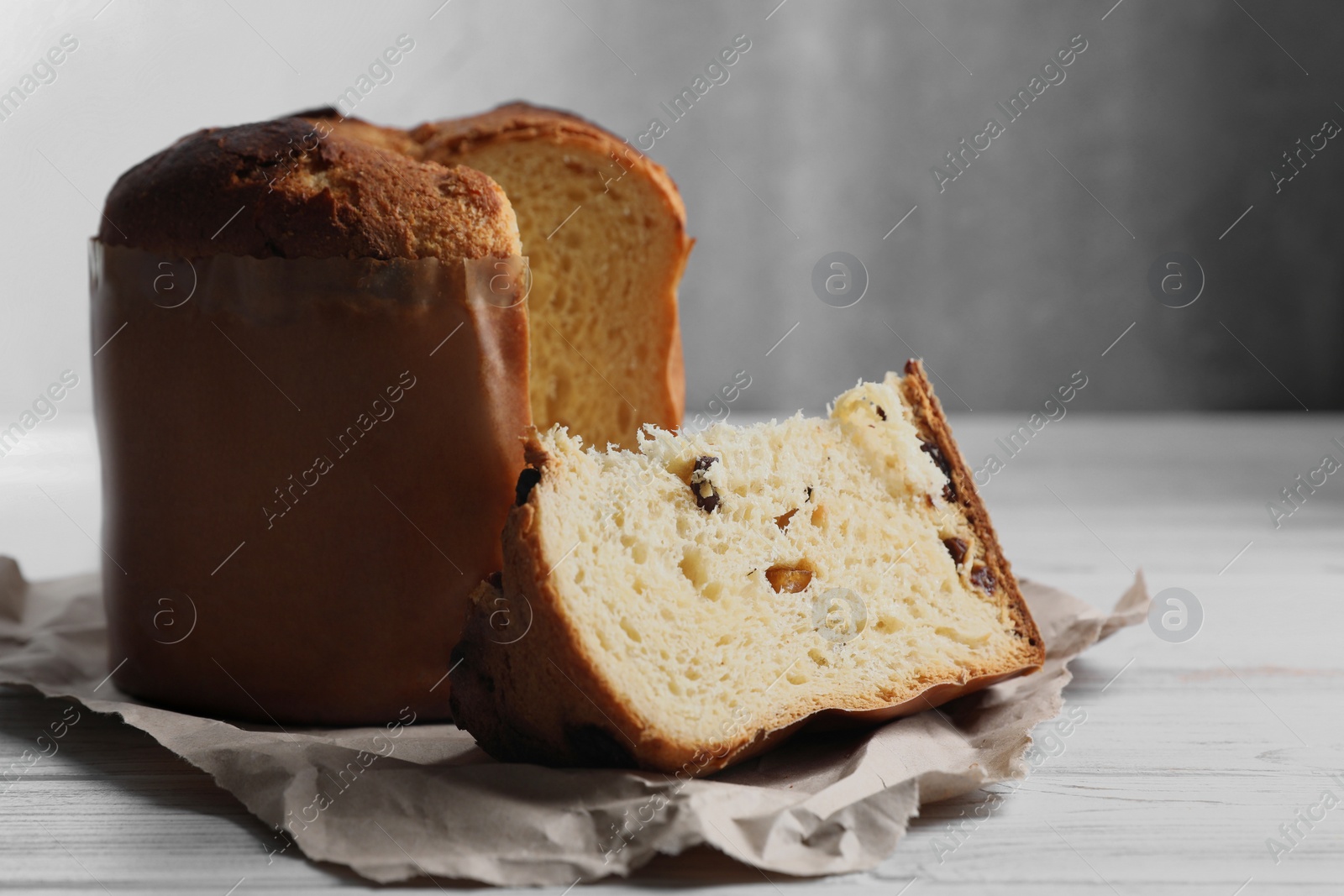 Photo of Delicious cut Panettone cake with raisins on white wooden table, space for text. Traditional Italian pastry