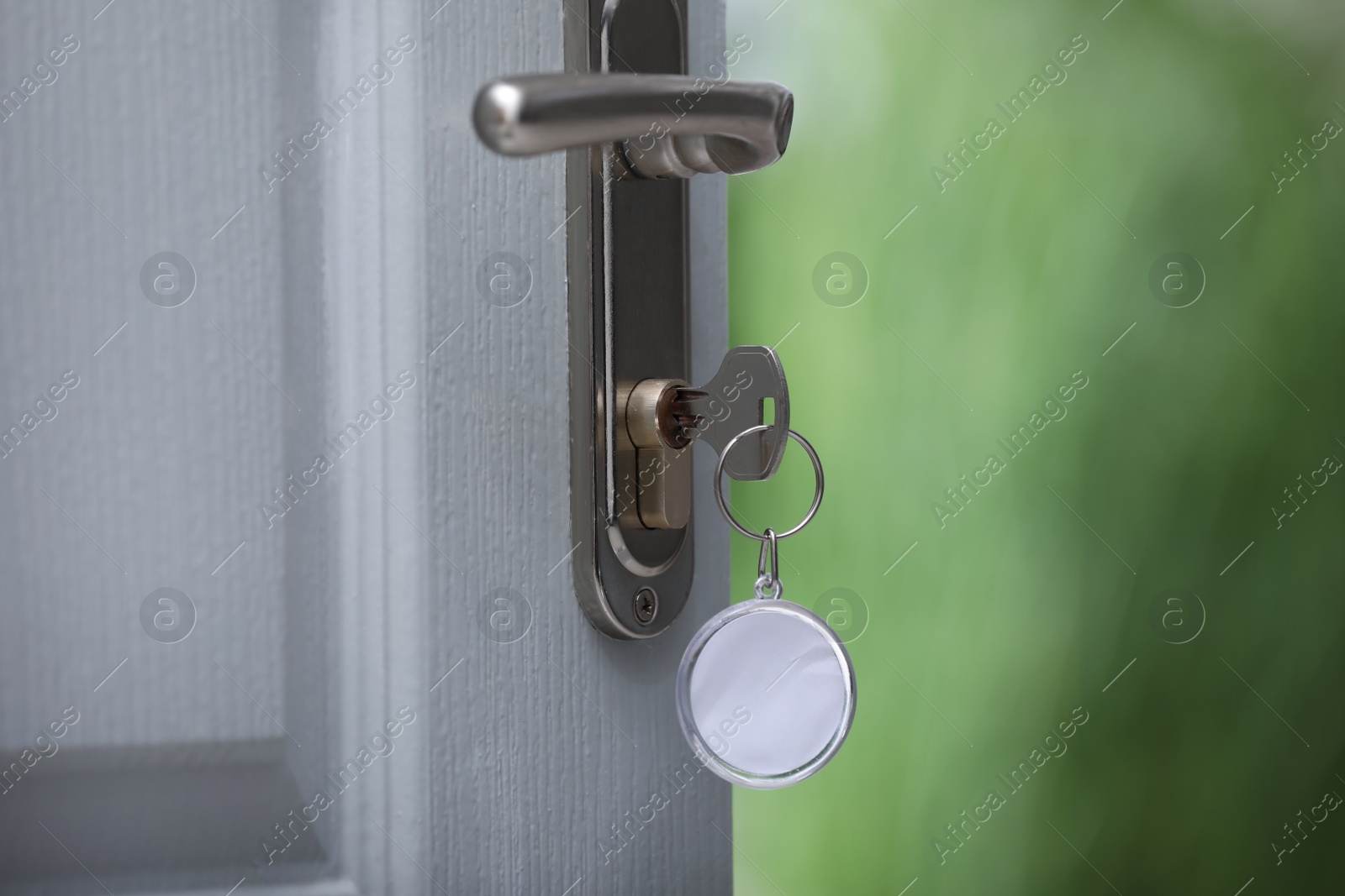 Photo of Open door with key on blurred background, closeup