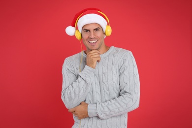 Happy man with headphones on red background. Christmas music