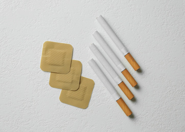 Nicotine patches and cigarettes on white background, flat lay