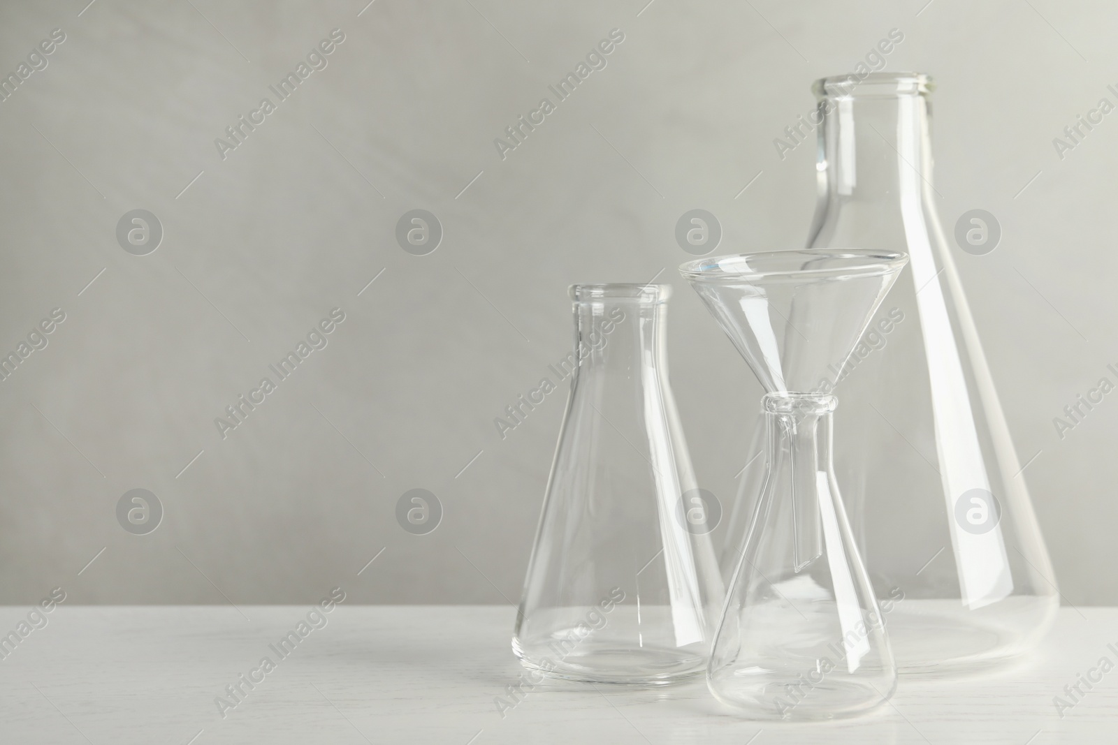 Photo of Set of laboratory glassware on white table against grey background, space for text