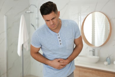 Photo of Man suffering from stomach ache in bathroom. Food poisoning