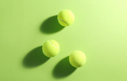 Tennis balls on green background, flat lay. Sports equipment