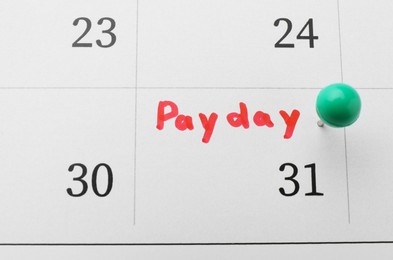 Photo of Calendar page with green pin on payday date, closeup