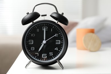 Photo of Black alarm clock on white nightstand in bedroom