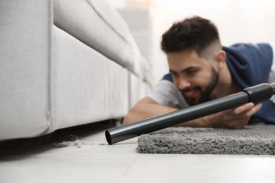 Young man using vacuum cleaner at home