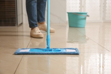 Photo of Woman cleaning floor with mop indoors, closeup