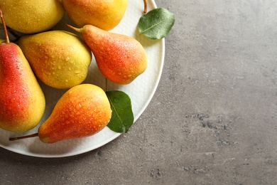 Photo of Plate with ripe pears on grey background, top view. Space for text