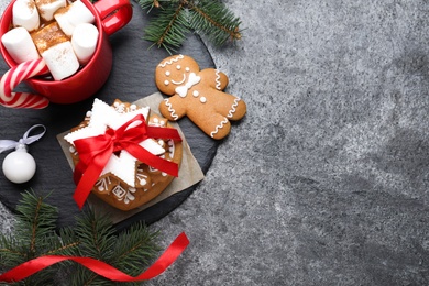 Decorated Christmas cookies and cup of delicious drink on grey table, flat lay. Space for text