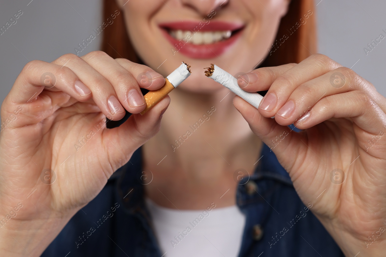 Photo of Stop smoking concept. Woman holding pieces of broken cigarette on light gray background, closeup