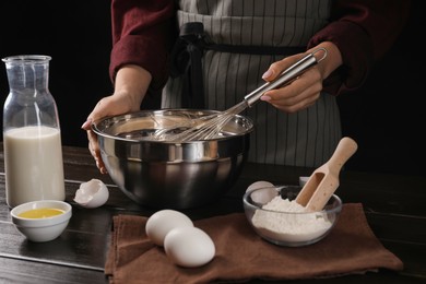 Photo of Woman making dough with whisk in bowl at table, closeup