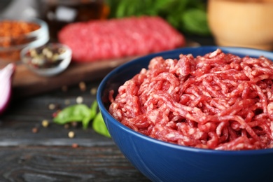 Fresh raw minced meat and vegetables on black wooden table, closeup