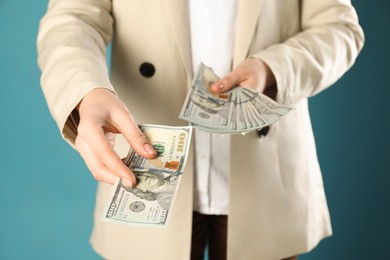 Photo of Woman holding dollar banknotes on turquoise background, closeup. Money exchange concept