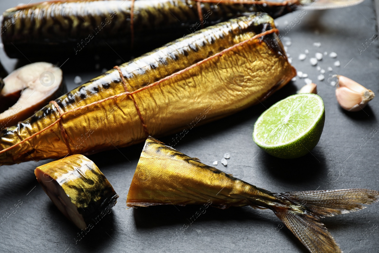 Photo of Tasty smoked fish on black table, closeup