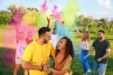 Photo of Happy couple covered with colorful powder dyes outdoors. Holi festival celebration