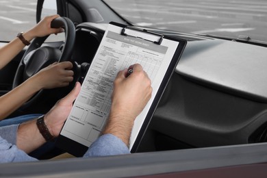 Driving school. Student passing driving test with examiner in car at parking lot, closeup