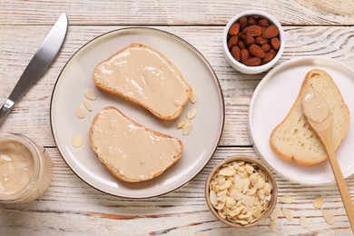 Photo of Toasts with tasty nut butter and almonds on light wooden table, flat lay