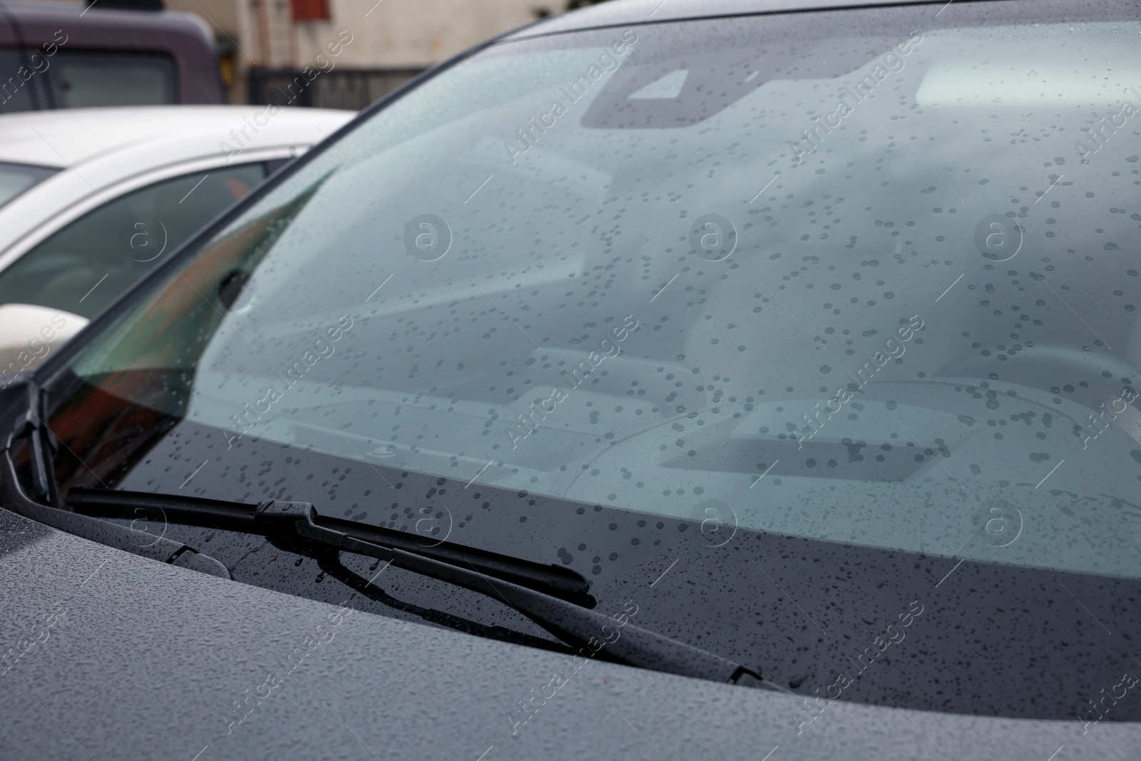 Photo of Car wiper cleaning water drops from windshield glass, closeup