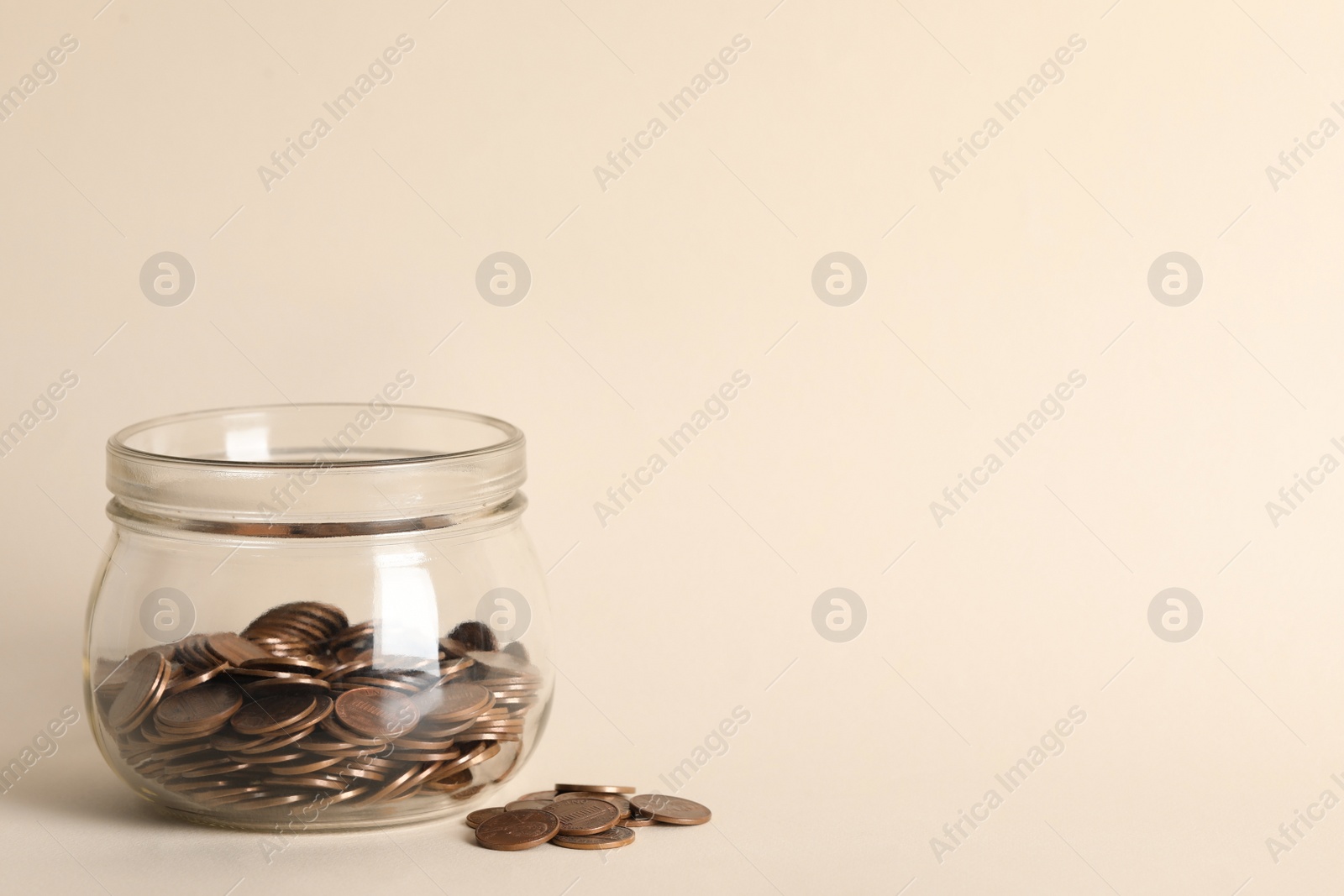 Photo of Glass jar with coins on beige background. Space for text