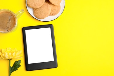 Flat lay composition with modern e-book reader on yellow background. Space for text