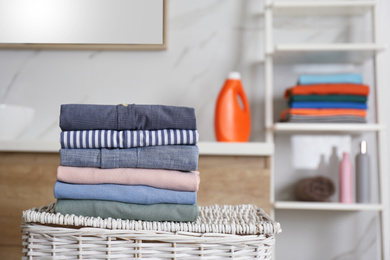 Photo of Stack of fresh laundry on basket in bathroom