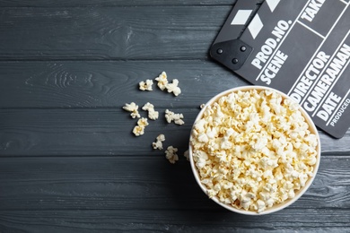 Popcorn and clapperboard on wooden background, top view with space for text. Cinema snack