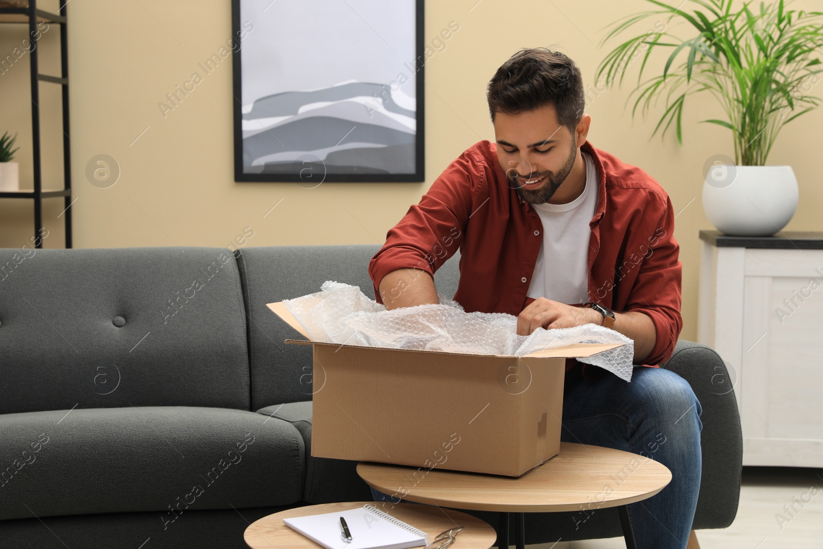 Photo of Man unpacking parcel at home. Online shopping
